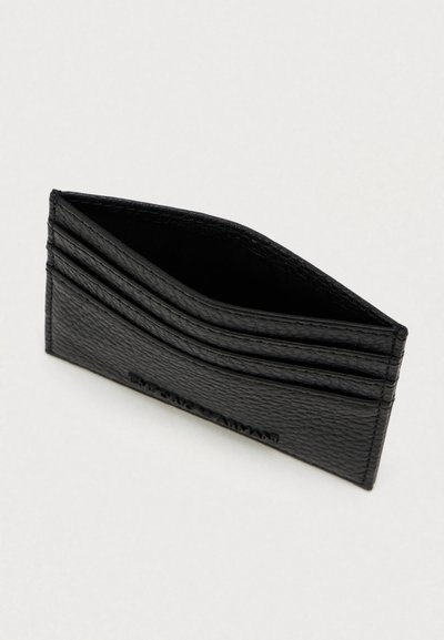 Carteira de cartão em couro preto texturado com três slots para cartões de cada lado e um compartimento central aberto num fundo branco.