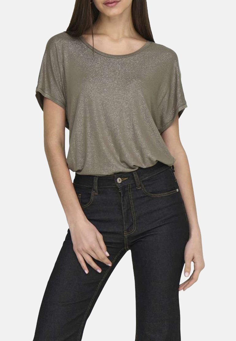 Top corto a maniche corte di un verde oliva metallico con una vestibilità ampia e scollo rotondo, abbinato a jeans blu scuro con cuciture a contrasto.