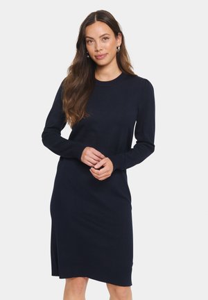Strickkleid in Marineblau mit langen Ärmeln, runder Halslinie, gerippten Bündchen und einem seitlichen Schlitz am Saum. Weicher Stoff und klassisches Design.