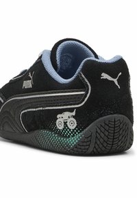 Tenisi din suede negru, cu un guler din plasă albastră, branding argintiu și un grafic cu un camion monstru pe lateral, având o talpă din cauciuc texturată.