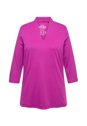 Top lungo a maniche lunghe in cotone rosa, morbido, con scollatura a V e maniche a tre quarti. Presenta una vestibilità comoda e un design minimalista.
