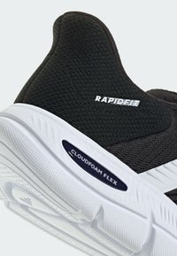 Chaussure de sport noire avec tige en mesh, semelle en caoutchouc blanche et détails texturés. Présente les étiquettes « RAPIDFIT » et « CLOUDFOAM FLEX ».