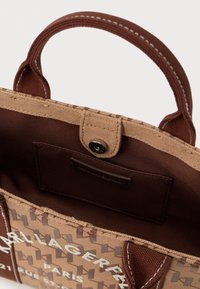 Hnědá textilní taška s texturovaným geometrickým vzorem, se zavřeným vrškem na patentku a krátkými, pevným uchy.