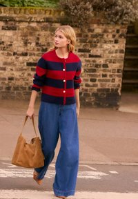 Röd och marinrandig cardigan med rund hals och knappar, tillsammans med vida blå jeans och en brun axelväska. Avslappnad outfit.