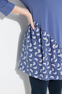 Top blu con un orlo curvo che presenta una gonna a fantasia. Il tessuto ha una texture morbida, con motivi bianchi e blu navy disposti in un pattern ciclico.