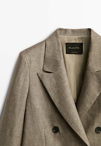 Blazer en lin marron clair avec deux boutons, col à revers cranté et une texture subtile. L'étiquette indique "Massimo Dutti", précisant la marque et l'origine.