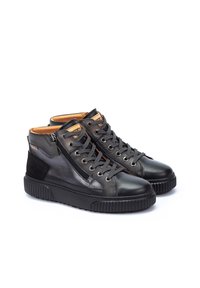 Zapatos altos de piel negra con un acabado texturizado, que cuentan con una cremallera lateral, cordones redondos y una suela de goma gruesa.