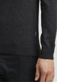 Dunkelgrauer Pullover mit strukturiertem Strick, gerippten Bündchen und einem leichten Seitenschlitz, versehen mit einem kleinen Markentag. Weiches, mittelschweres Material.