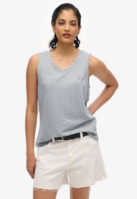 Maglietta senza maniche grigia chiara in tessuto misto cotone, con scollatura tonda e vestibilità rilassata, abbinata a pantaloni cargo bianchi.