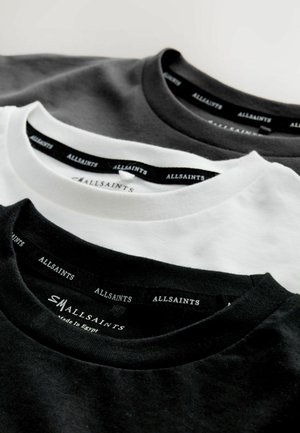 Tre crew-neck t-shirts præsenteret: en sort, en hvid og en mørkegrå. Alle har "ALLSAINTS" brandetiketter på sorte nakkemærker.