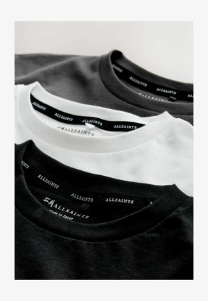 Trzy koszulki typu crew neck wyeksponowane: jedna czarna, jedna biała, jedna ciemnoszara. Wszystkie mają metki marki "ALLSAINTS" na czarnych etykietach przy dekolcie.