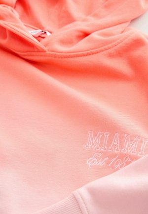 Sudadera con capucha de color rosa coral hecha de algodón suave, con "MIAMI" y "Est. 1987" en bordado blanco, y puños y dobladillo acanalados.
