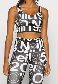 Svart atletisk crop top och höga leggings, med stora vita siffror och en subtil logotyp i neongul, tillverkad av stretchmaterial.