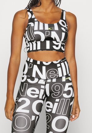 Top corto atlético negro y leggings de cintura alta, con grandes números blancos y un discreto logo en amarillo neón, fabricados con material elástico.