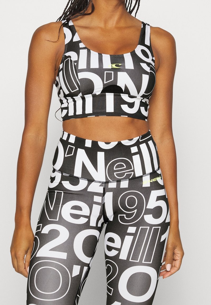 Svart atletisk crop top och höga leggings, med stora vita siffror och en subtil logotyp i neongul, tillverkad av stretchmaterial.