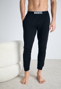 Joggers noirs en coton avec une taille élastique et un logo contrasté ; coupe ajustée avec des poches latérales et des chevilles resserrées.