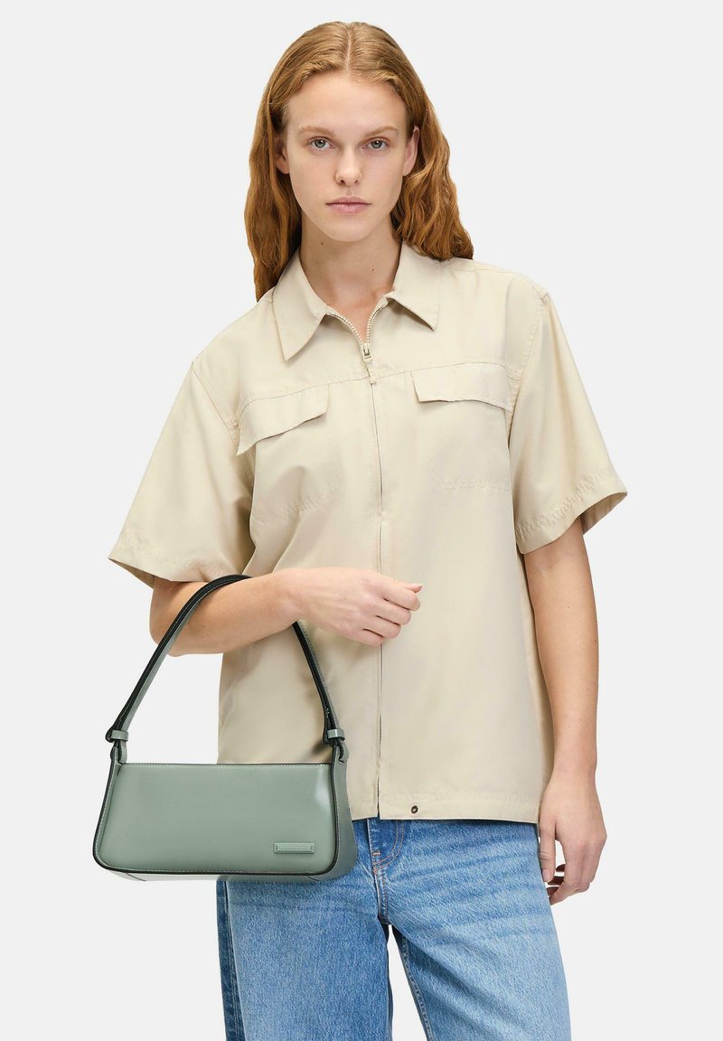 Borsa a mano grigio-verde con un design strutturato e una texture liscia. Presenta una maniglia nera e un sottile dettaglio del marchio.