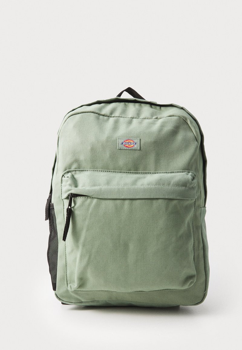 Roheline kangast seljakott, millel on lukkuga esikott, mustad võrkpoolsed taskud ja ülal käepide. Esiküljel logo patch.