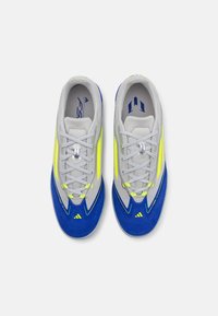 Zapatillas deportivas en gris, azul y amarillo neón. Presentan una parte superior suave con acentos de ante, cordones y un interior acolchado. Diseño aerodinámico.