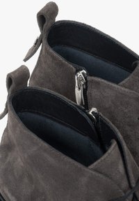 Szare zamszowe botki za kostkę o miękkiej fakturze, z widocznymi suwakami i materiałowymi pętelkami ułatwiającymi zakładanie; wnętrze wyłożone czarnym materiałem.