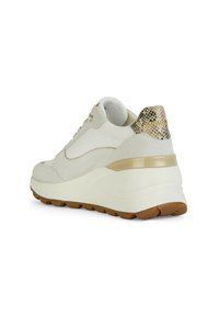 Baskets en suede blanc avec un accent texturé doré et noir au niveau du talon. Semelle blanche épaisse avec une semelle extérieure en caoutchouc brun. Œillets dorés.