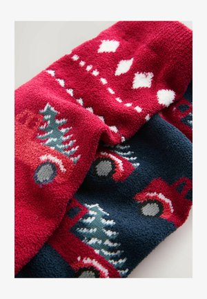 Two plush blankets: one red with white diamond patterns and trees, the other navy featuring red trucks and trees, both textured and cozy.