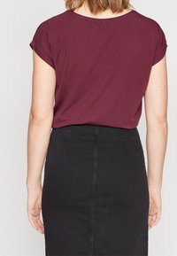 Burgundská krátký rukáv top s volným střihem, nad pas, kombinovaný s přiléhavou černou džínovou sukní. Jemná textura, základní design.