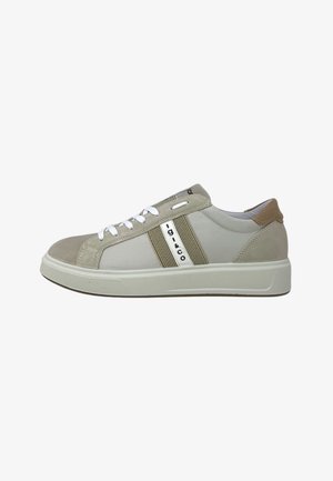 Sneaker basse beige e panna con lacci bianchi, striscia laterale texturizzata e toppa marrone sul tallone su una suola spessa bianca.