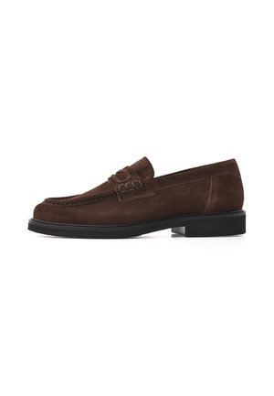Dunkelbrauner Wildleder-Slipper mit schwarzer Sohle, niedrigem Absatz und dekorativem Riemen oben.