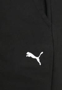 Zwarte sweatpants met een gladde textuur, voorzien van een wit Puma-logo aan de linkerkant. Inclusief zijzakken en een geribbelde tailleband.