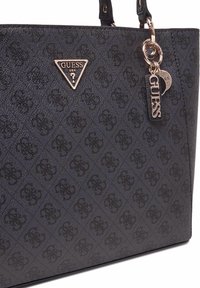 Zwarte handtas met textuur en een diamantpatroon, met een driehoekig roségouden logo-tag en extra charme accenten.