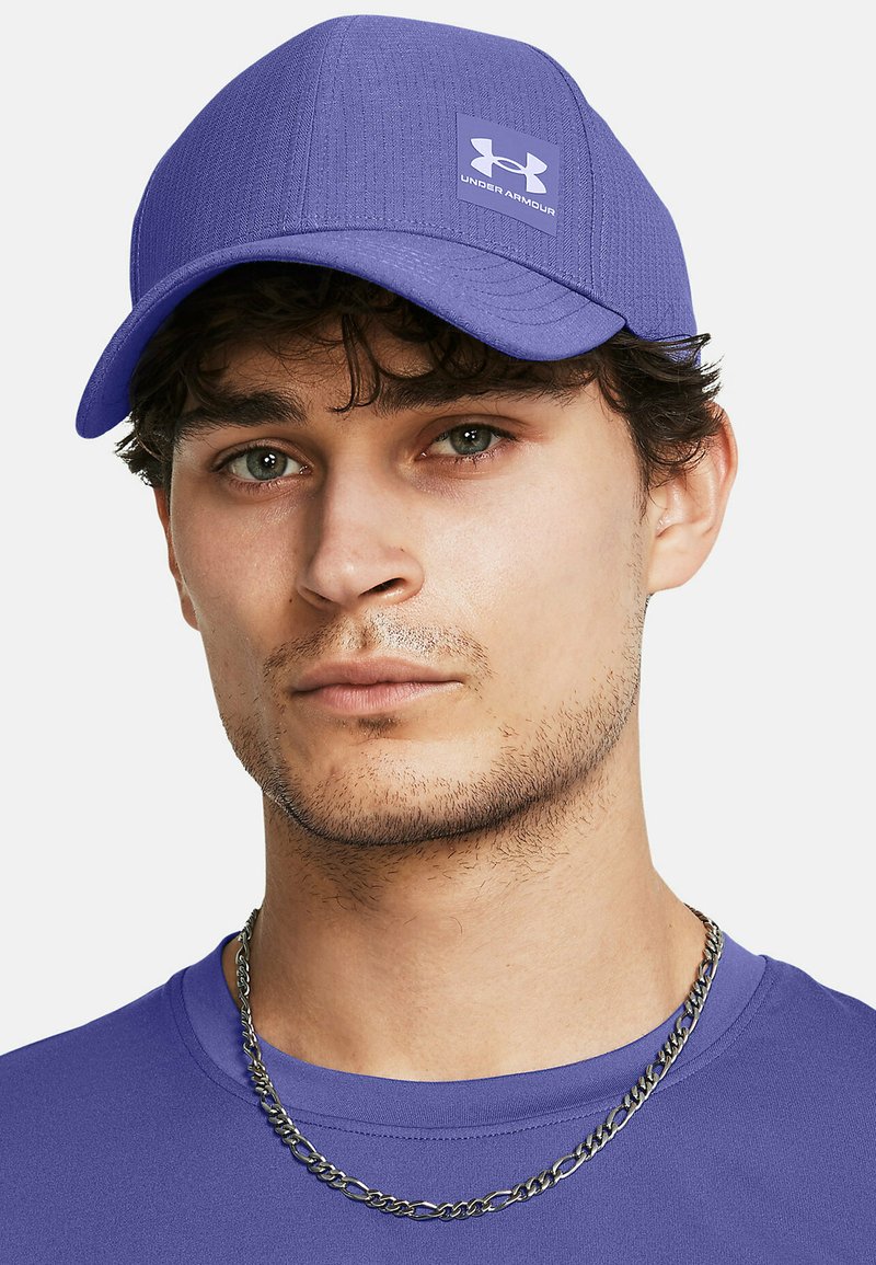 Lila Kappe mit strukturiertem Design und kleinem Under Armour-Logo-Patch; hat einen gebogenen Schirm und eine glatte Stoffoberfläche.