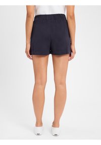 Marineblauwe, hoge shorts gemaakt van lichtgewicht stof. Voorzien van een elastische tailleband en een ontspannen pasvorm, eindigend op halverwege de bovenbenen.