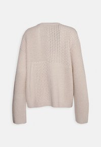 Maglione lavorato a maglia beige chiaro con un design a patchwork caratterizzato da texture e motivi vari, maniche lunghe e una vestibilità rilassata.