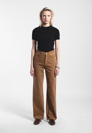 Chemise noire à manches courtes associée à un pantalon marron taille haute à jambes larges en coton robuste. Comprend des poches avant classiques et une fermeture à boutons.