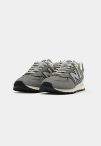 Sneaker grigie con suede texturizzato, dettagli in rete, logo bianco e grigio, suola in gomma nera e lacci piatti. Design atletico classico.