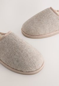 Sivé tkané vlnené papuče s jemnou podšívkou, s béžovým lemom a zaoblenou špičkou. Protišmyková podrážka pre stabilitu.