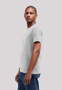 Gray short-sleeve t-shirt with a crew neck, made from soft fabric. Features a subtle graphic on the front, paired with blue denim jeans.