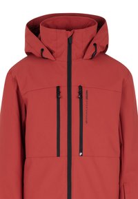 Giacca impermeabile rossa con colletto alto e cappuccio. Presenta due tasche nere con cerniera e dettagli con logo lungo la linea della cerniera.