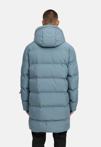 Šviesiai mėlynas pūkinis paltas su gobtuvu, turintis siuvinėtą dizainą, ilgomis rankovėmis ir laisvu siluetu, siekiančiu vidurinę šlaunų dalį.