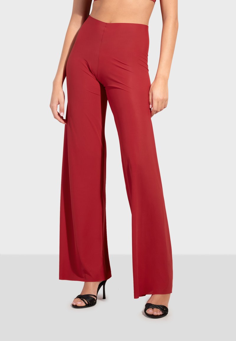 Röda vida byxor i elastiskt material med hög midja och slät yta, stiliga tillsammans med svarta sandaler med remmar.