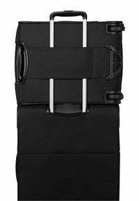 Valigia nera morbida con manico telescopico esteso, maniglia laterale e quattro ruote, vista dall'alto.