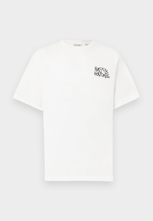 T-shirt branca de manga curta feita de algodão, com um gráfico preto com a frase "FELIZES FÉRIAS" na área do peito esquerdo.