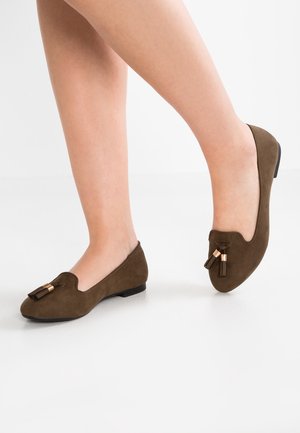 Brune ruskinds flade sko med rund tå, prydet med en dekorativ kvast og detaljer i guldtonet metal på overdelen, lav hæl og glat finish.