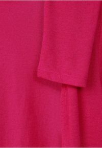 Fuksianvärinen puuvillainen t-paita, jossa on lyhyet hihat, sileä pinta ja rento istuvuus. Hihoissa ja helmassa näkyvät ompeleet.