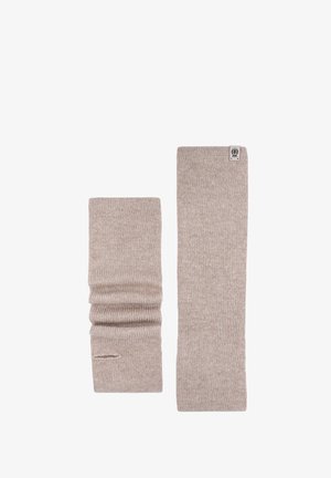 Ein Paar beiger gestrickter Armwärmer, einer flach ausgelegt und der andere gerafft, mit sichtbarem Daumenloch.