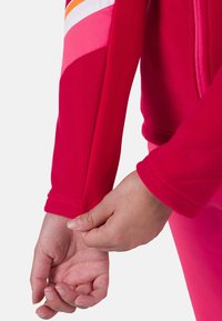 Fleece bunda v živé růžové barvě s barevně rozdělenými rukávy, které mají akcenty v oranžové, bílé a tmavě růžové. Rukávy jsou přiléhavé a mají hladkou texturu.