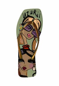 Flip-flop met een groene geprinte zool met artistieke gezichten. Gouden banden en decoratieve rhinestones verbeteren het ontwerp. Tekst "uzurii" zichtbaar.