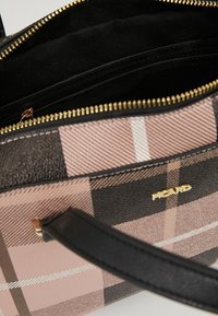 Torebka w kratkę w kolorach różowym, czarnym i białym. Teksturowany materiał zewnętrzny, złoty zamek błyskawiczny i czarne wykończenie z tkaniny. Posiada czarny uchwyt.
