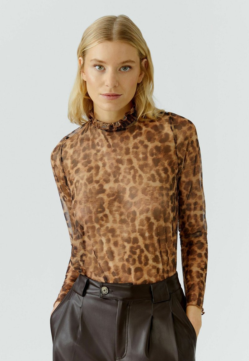 Langarmtop in doorschijnende bruine stof met een panterprint, met een gerimpelde hoge halslijn en een getailleerd silhouet, gecombineerd met donkere broek.